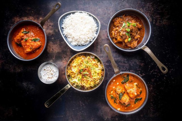 A vibrant Indian feast featuring aromatic biryani, rich curry, and cooling raita, beautifully arranged for a Mother's Day celebration at Masalchi.