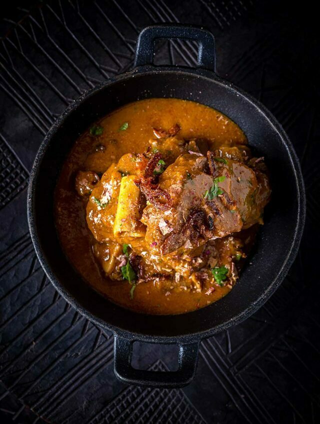A traditional mutton handi curry garnished with crispy fried onions, showcasing the authentic Indian street food flavours crafted by Chef Atul Kochhar.