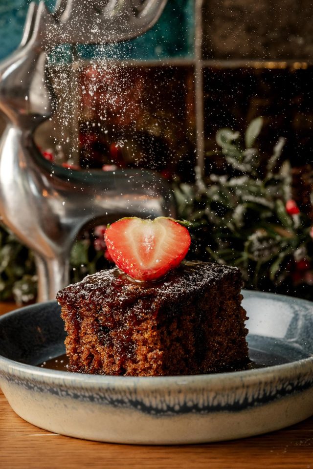 A decadent caramel cake topped with fresh strawberries, served as a festive dessert at Chef Atul Kochhar's casual dining restaurant