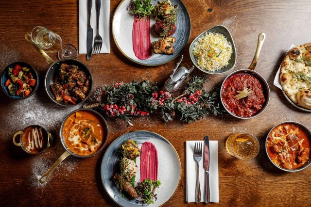 A vibrant festive Indian feast featuring rich curries, tandoori chicken tikka, and warm naan bread at Masalchi in Wembley Park.