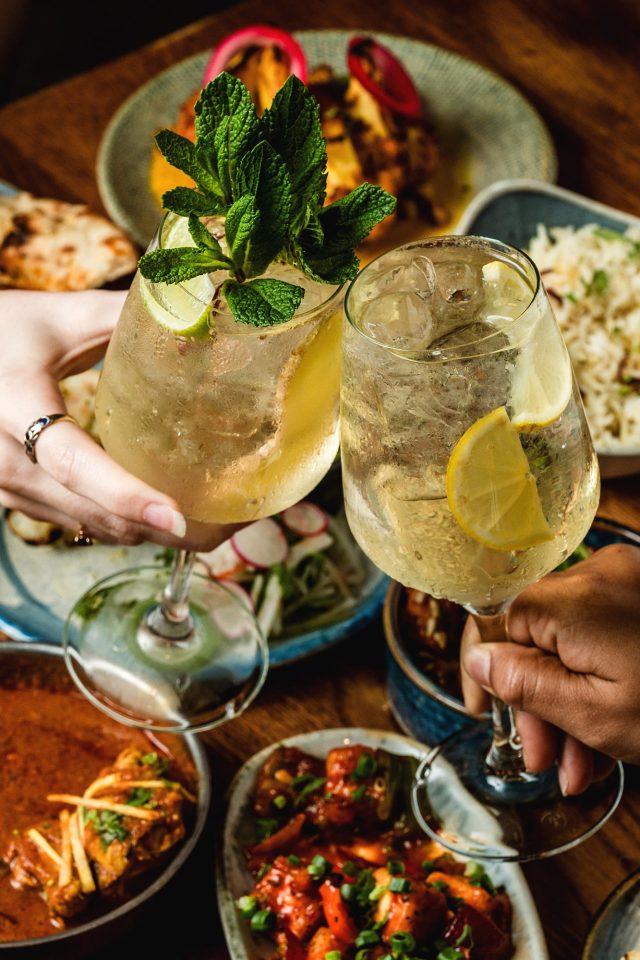 Guests clinking cocktails over a pre-event Indian feast at Masalchi Wembley Park.